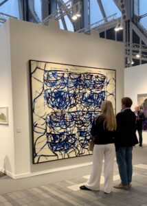 Visitors standing in front of a painting by Rashid Johnson at Hauser & Wirth's booth at Frieze 2025.
