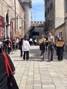 A woman holding a sign "Hope for Peace" in front of the line to enter the Arsenale.